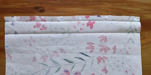 The top edge of the floral fabric folded down twice and creased flat to create a hem.