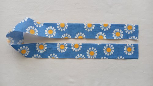 A long, narrow strip of blue fabric with a white and yellow daisy pattern.