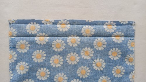 A piece of blue floral fabric with two parallel horizontal ironed creases near a top edge.
