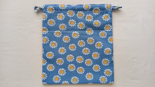 A blue floral drawstring bag with two fabric ties knotted together on each side.