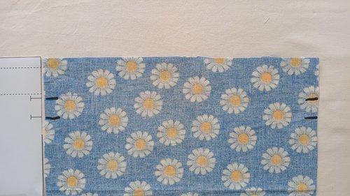 A light blue underside of a floral fabric showing small pencil marks near a side edge.