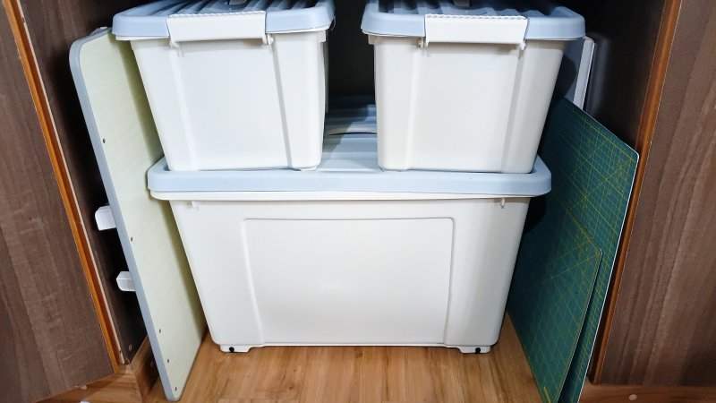 Fabric storage inside a wardrobe, with fabric and sewing materials organized in lidded storage bins.