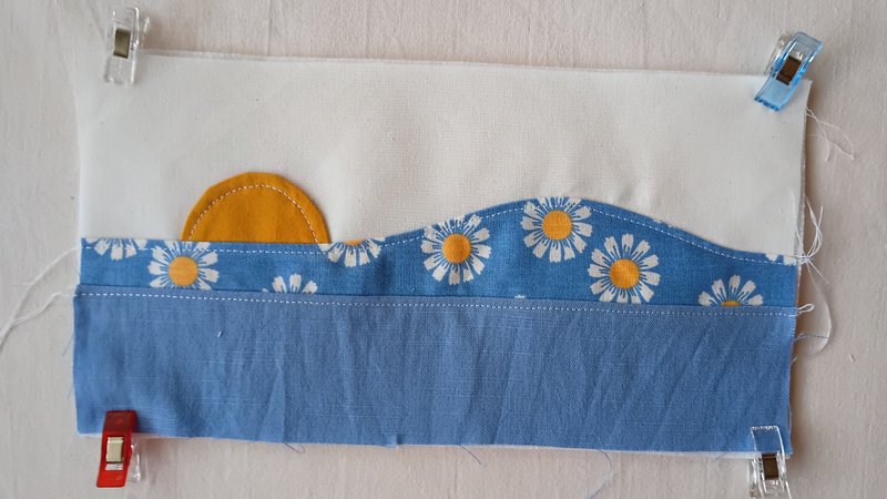 A patchwork rectangle of fabric clipped at the four corners. The applique is topstitched