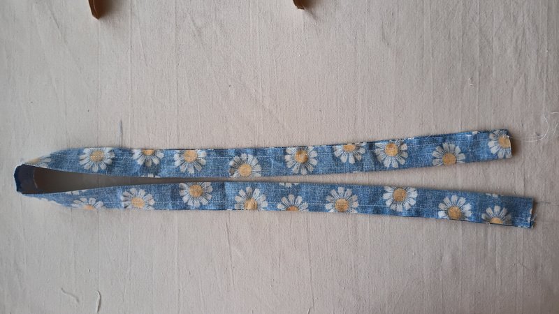 Daisy print fabric strip sewn into a tube, wrong side out, sewing line visible along the edge.