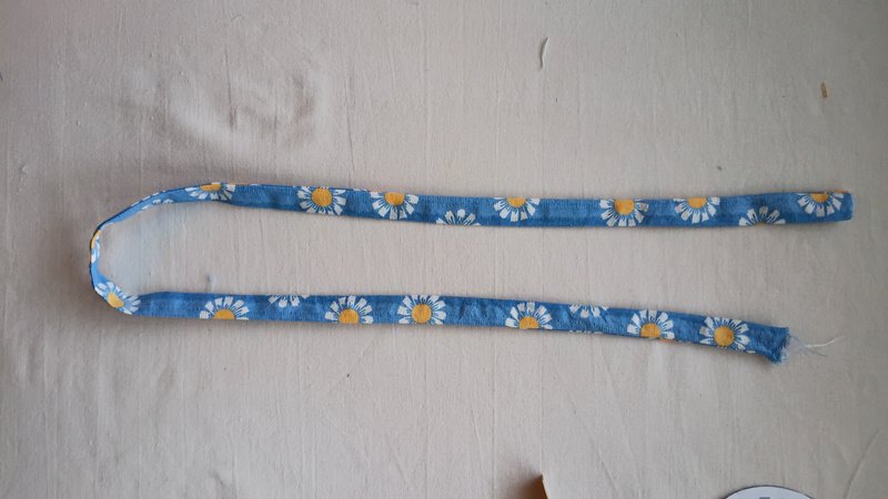 Daisy print fabric casing turned right side out, forming a long tube for the elastic strap.