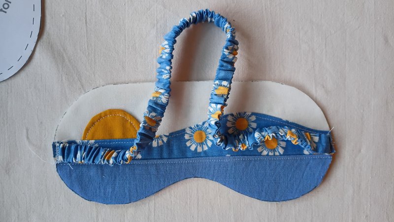 A fabric covered elastic strap sewn onto sleep mask front.