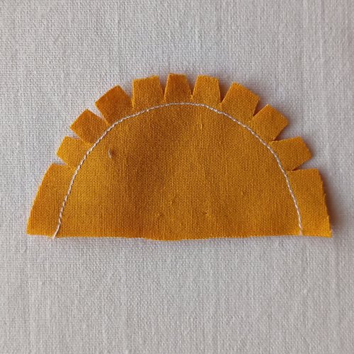 Semi circle of yellow fabric with a line of stitching and notches clipped in the seam allowance