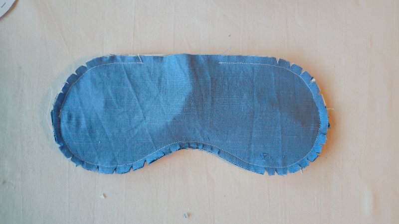 Sleep mask seam allowance clipped and notched around the curved edges, showing topstitching line.