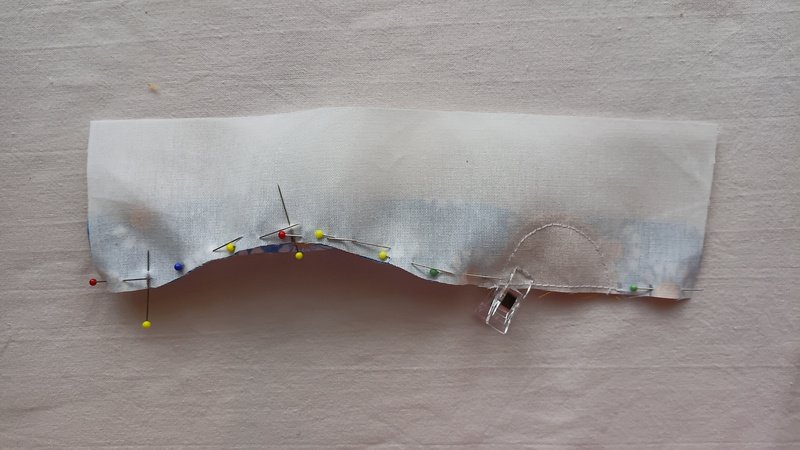 Off-white fabric pinned onto a blue floral fabric.