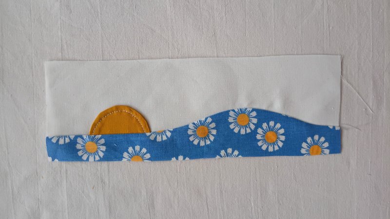 Sun appliqué sewn onto a floral fabric and off-white fabric on top.