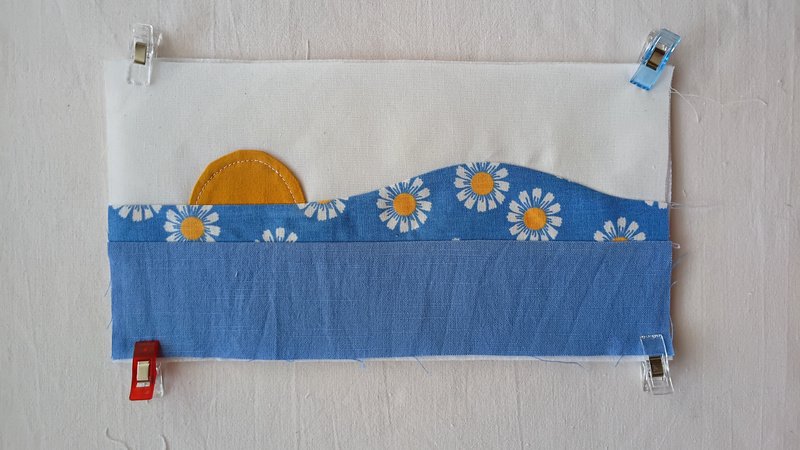 A patchwork rectangle of fabric clipped at the four corners