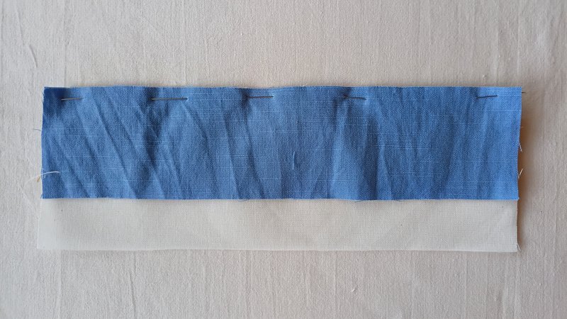 A rectangle of blue fabric pinned onto an off-white rectangle