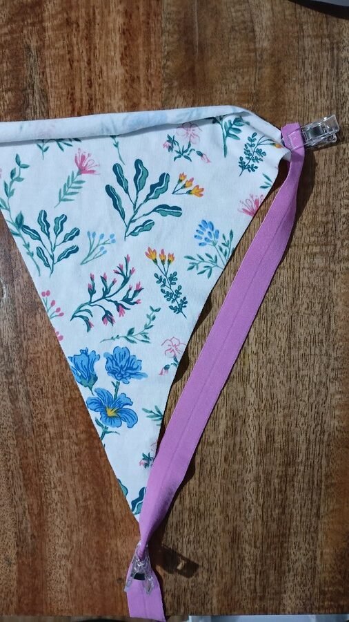 Triangular piece of floral fabric clipped to pink fold over elastic