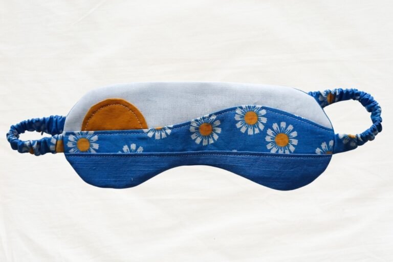 Blue, white, and yellow patchwork sleep mask on an off-white fabric