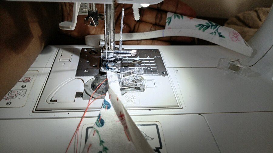 Close-up of fold-over elastic being sewn onto the fabric with a zigzag stitch while gently stretching the elastic.