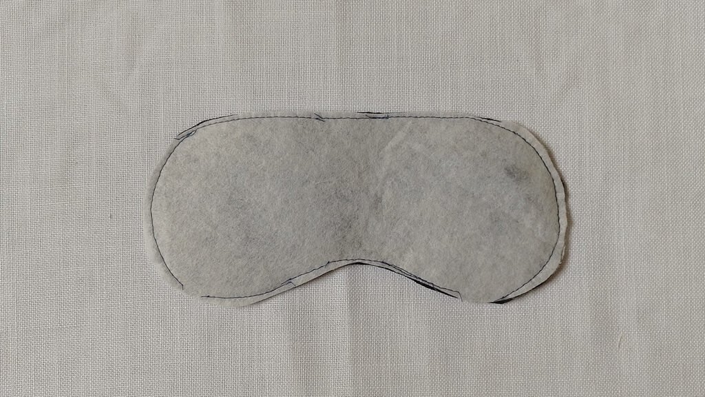 This is an image of the back of the mask front. It is a basted layer of batting and black velvet fabric.