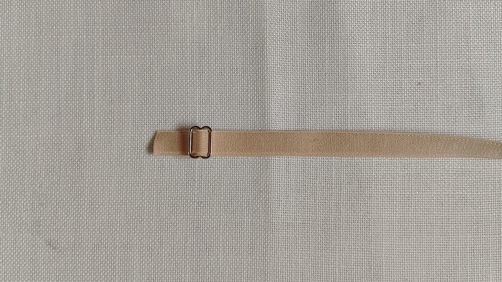 A beige elastic strap inserted into a silver slider at one end