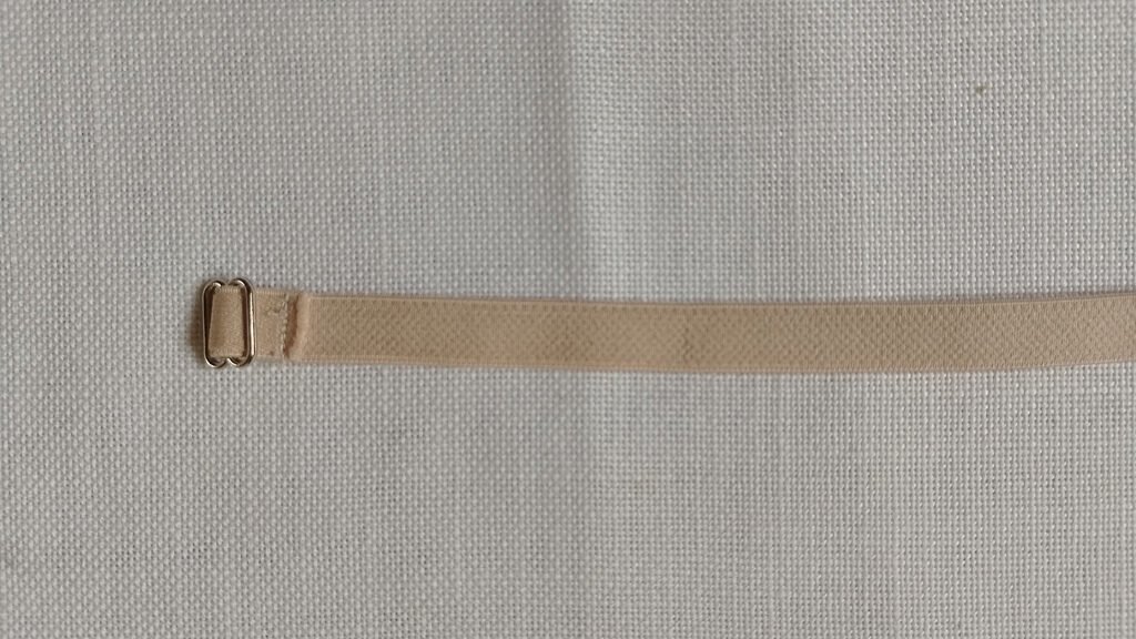 Beige strap elastic threaded into a silver slider and sewed.