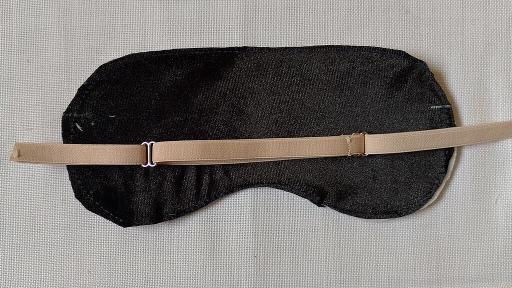 The front piece of a sleep mask and a beige adjustable strap