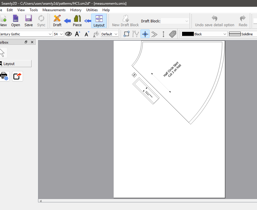 Seamly2D in Layout mode showing a single page with the half circle skirt piece, its label and grainline, and the small waistband piece placed along its edge.