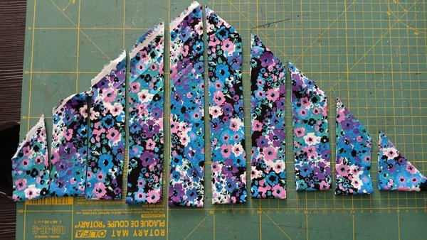 Floral fabric cut into bias strips laid out on a cutting mat