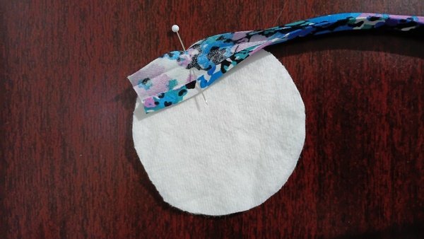 Floral bias tape being guided onto a flannel round with a bamboo tool at the sewing machine