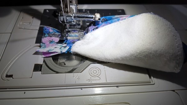 Two floral bias tape ends being sewn together under the sewing machine foot