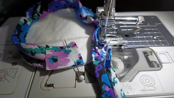 Pinned bias tape join on a flannel round while sewing at the machine