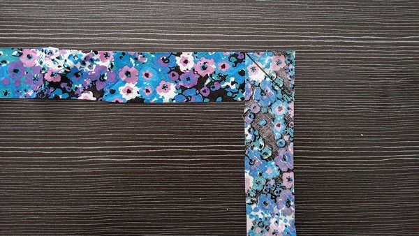 Two floral fabric strips pinned right sides together at a right angle with a stitched diagonal line