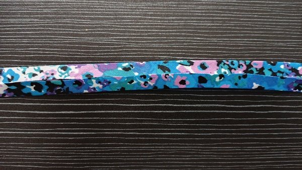 Narrow folded floral bias tape laid flat on a dark wood table