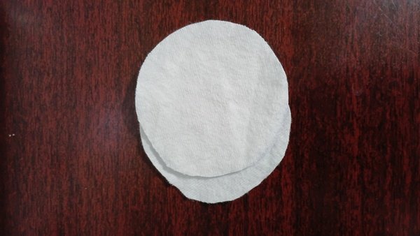Round of white flannel fabric cut out on a dark wood table